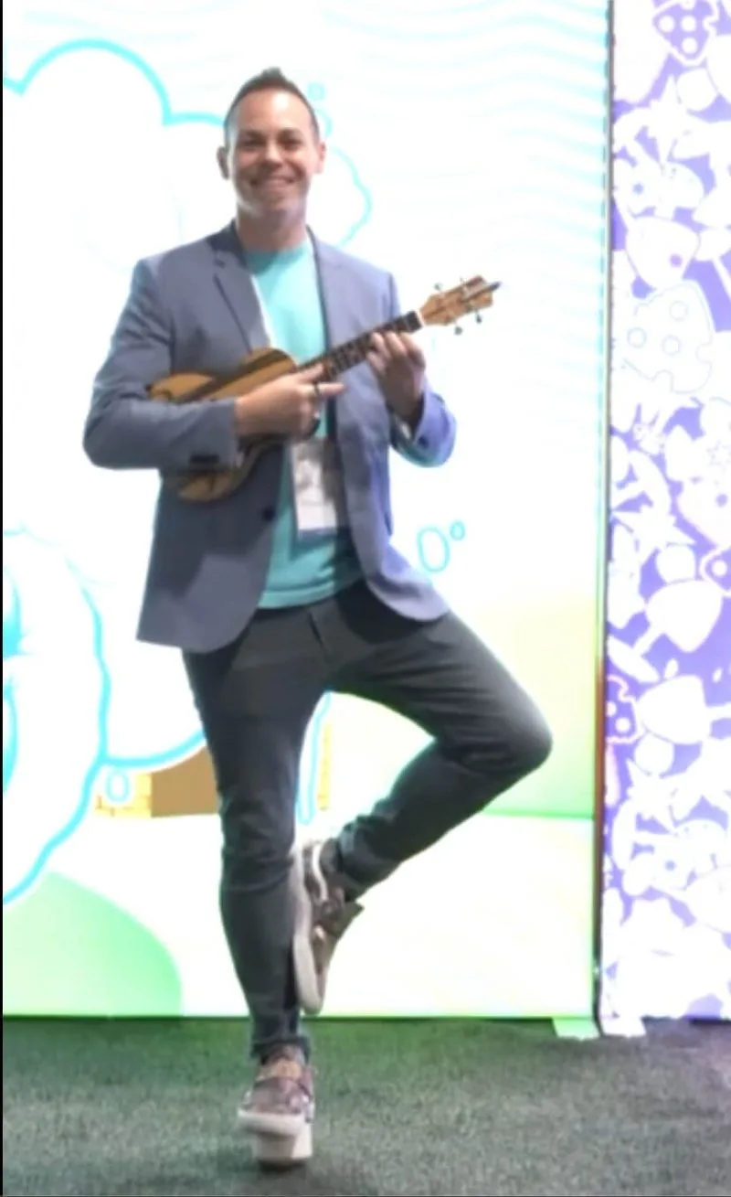 Ryan Today playing ukulele while balancing on one leg at a conference